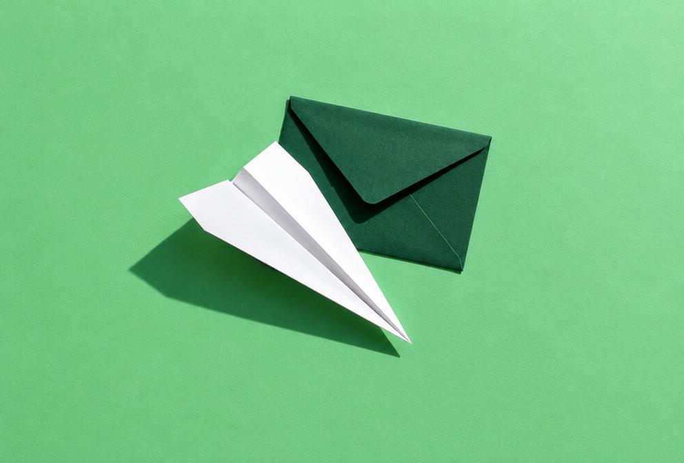 Paper airplane and envelope on a mint green desk